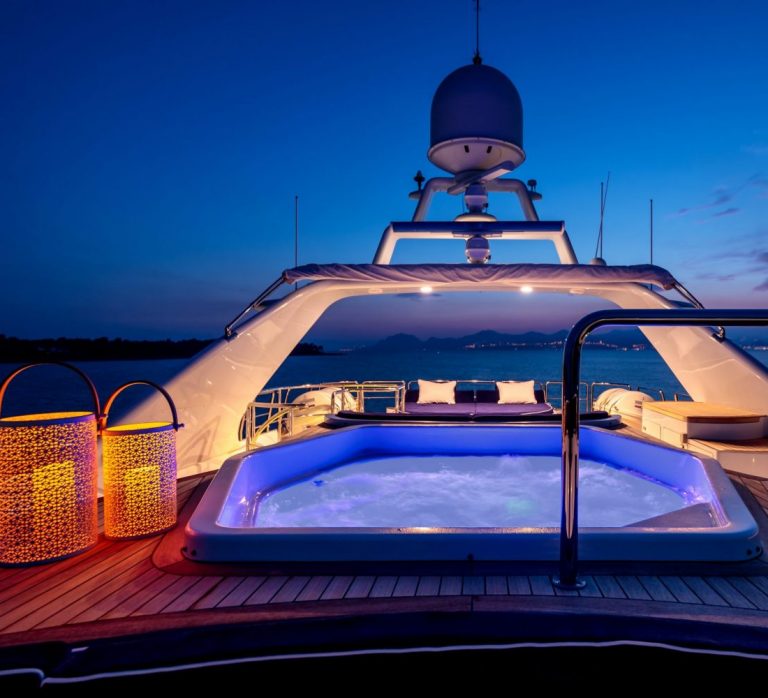 Luxury yacht with lights and a jacuzzi sailing in the sea at night